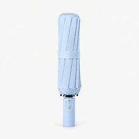 Folded light blue umbrella standing upright on a white background, held closed by a fabric strap. 6