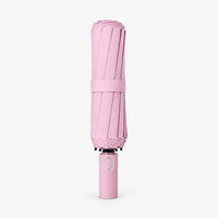 Folded pink umbrella with strap, standing upright on a white background with the handle at the bottom. 7