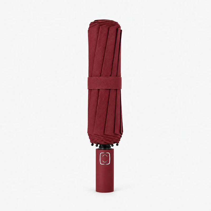 Folded dark burgundy umbrella standing upright on a white background, closed with a matching strap. 9