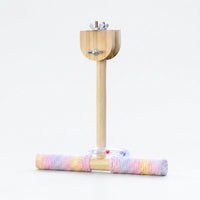 Wooden T-shaped perch with pastel rope-wrapped crossbar, a clear ring with coloured beads and wing-nut clamp at the top, on white. 1