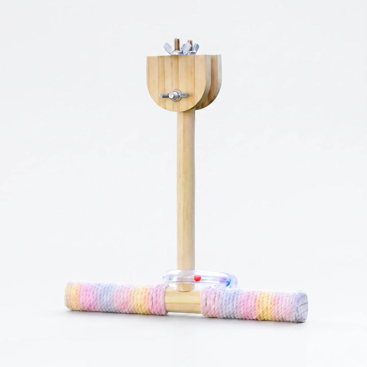 Wooden T-shaped perch with pastel rope-wrapped crossbar, a clear ring with coloured beads and wing-nut clamp at the top, on white. 1