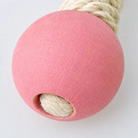 Close-up of a pink painted wooden bead on the end of a sisal rope arm, showing the rope threaded through the hole. 4