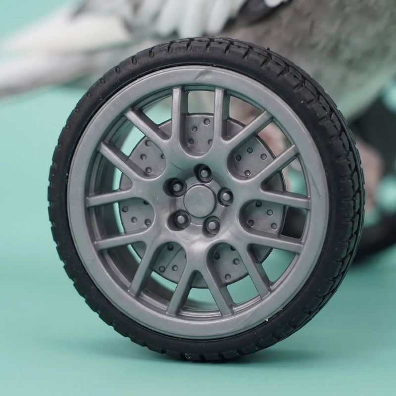 Close-up of one wheel showing its grey multi-spoke rim and black treaded tyre, with the bird blurred behind. 3