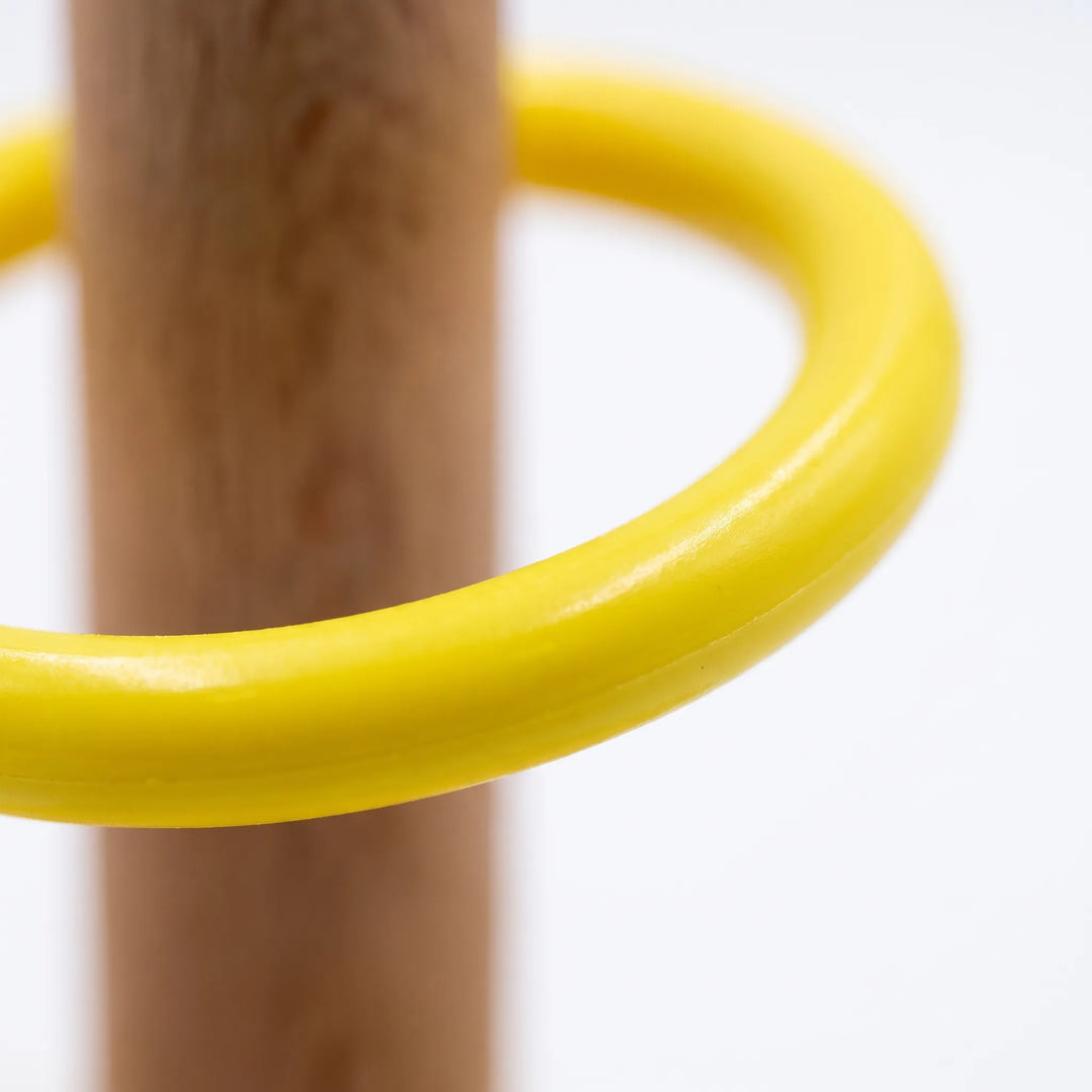 Close-up of a smooth yellow plastic ring resting around the wooden peg, showing the glossy finish against a plain white background. 4