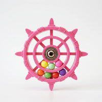 Pink ship's-wheel bird toy with a metal bearing hub and seven coloured balls, shown on a plain white background. 1
