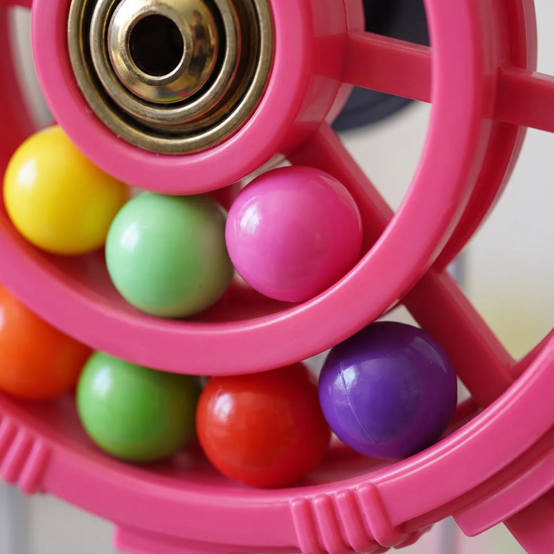 Close-up of the metal bearing hub and the glossy coloured balls rolling inside the pink wheel's rings. 3