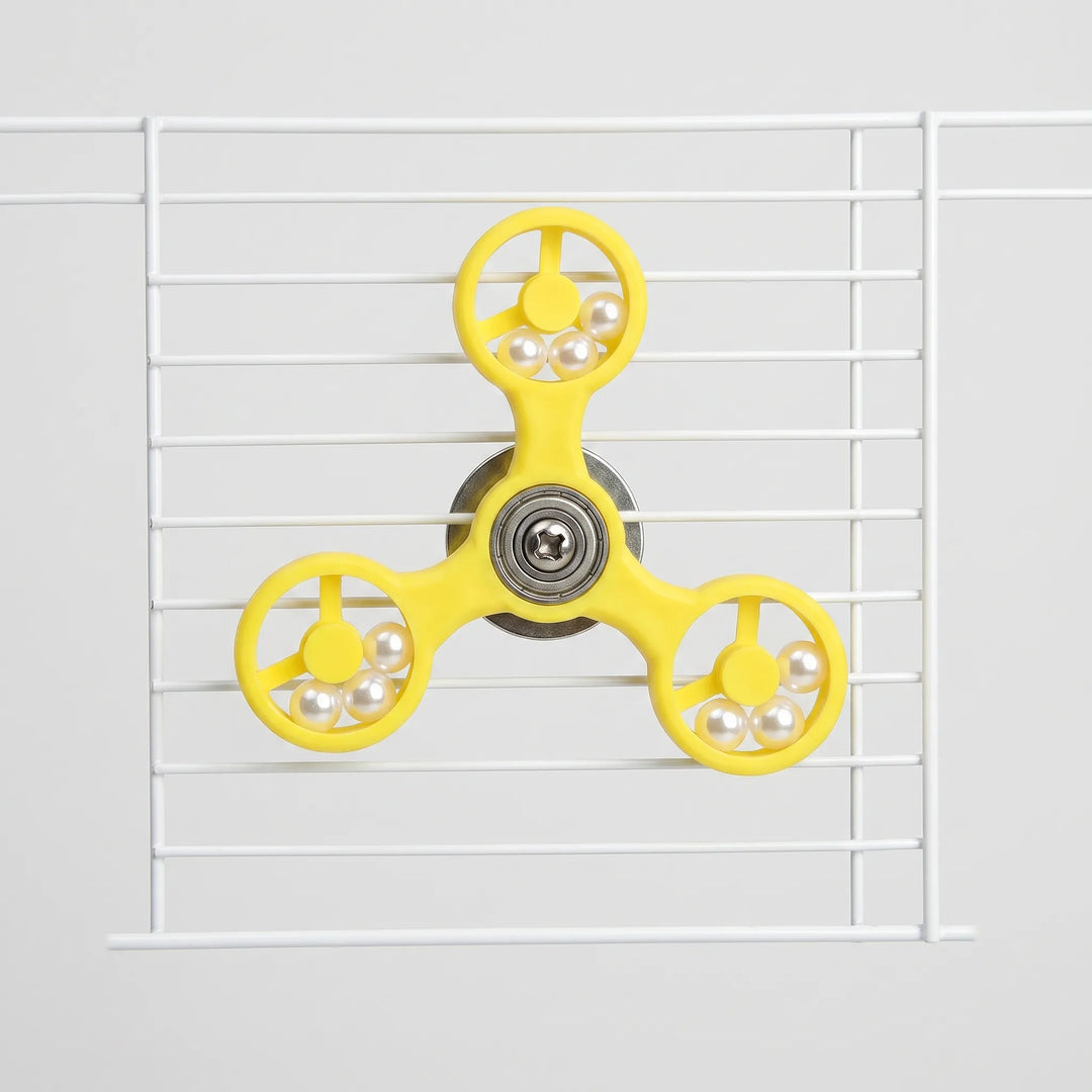 Front view of the yellow three-armed spinner toy fixed to white cage bars, with pearl beads in each ring. 1