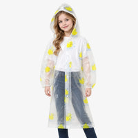 Front view of a smiling girl wearing a clear hooded raincoat with yellow rubber ducks, elastic cuffs and snap buttons. 4