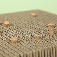 Close-up of the honeycomb-like cardboard surface and the cork stoppers set into it, against a pale green background. 4