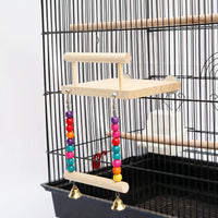 Wooden bird platform with perch rail and a bead-and-bell swing below, fixed to the bars of a black cage. 1