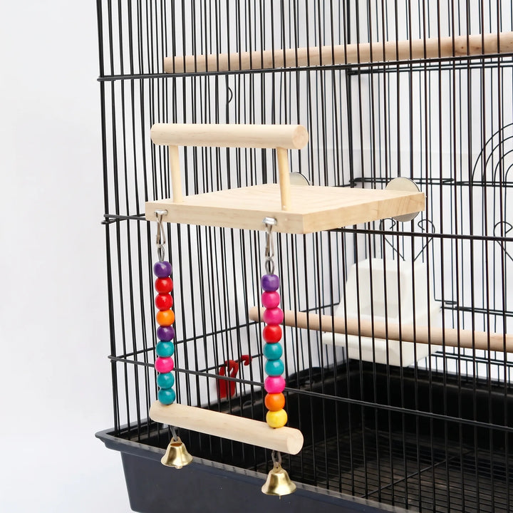 Wooden bird platform with perch rail and a bead-and-bell swing below, fixed to the bars of a black cage. 1