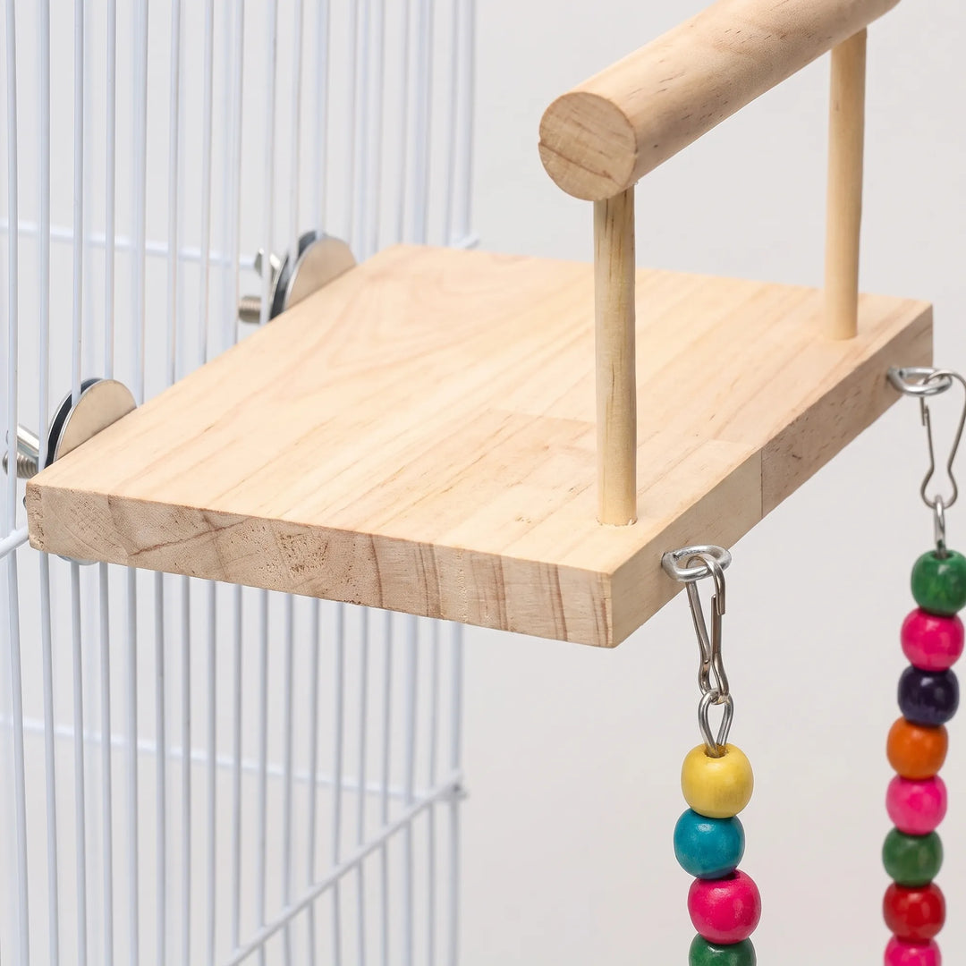 Close-up of the pale wooden platform, its metal discs and screws clamped to the cage bars, with hooks and coloured beads hanging. 3