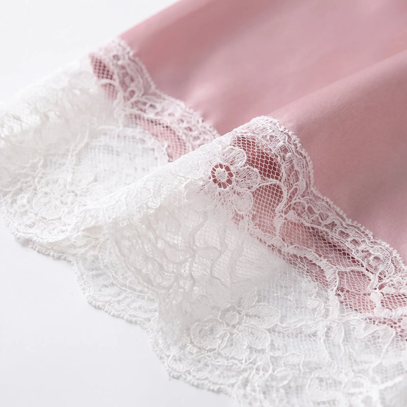 Close-up of white floral lace trim on the pink satin fabric, showing its scalloped edge and mesh detail. 4