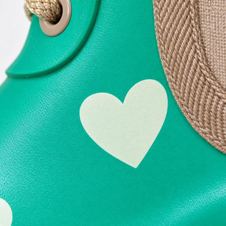 Close-up of a pale heart print on glossy green rubber, with a metal lace eyelet and woven elastic gusset edge. 6