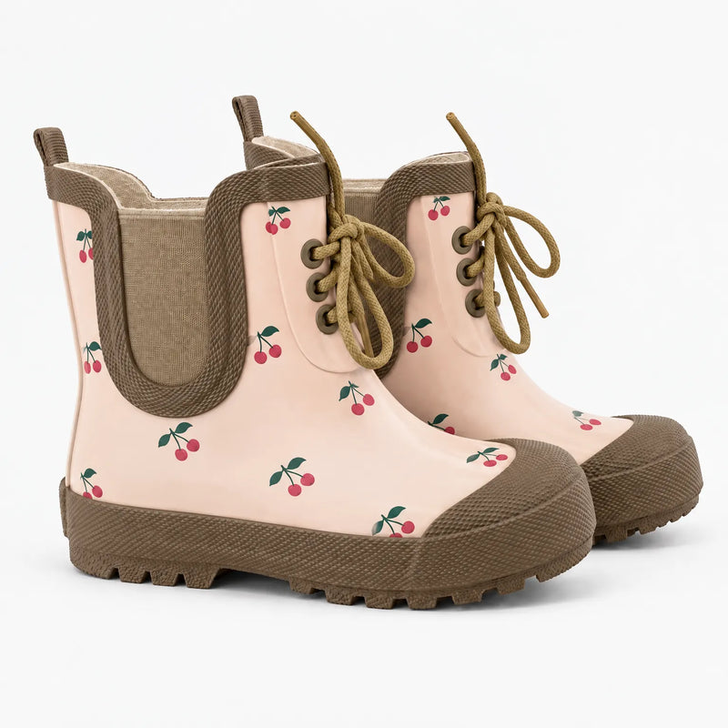 Pair of lace-up rubber boots in soft pink with a red cherry print, tan trim, elastic side panel and lugged sole. 7