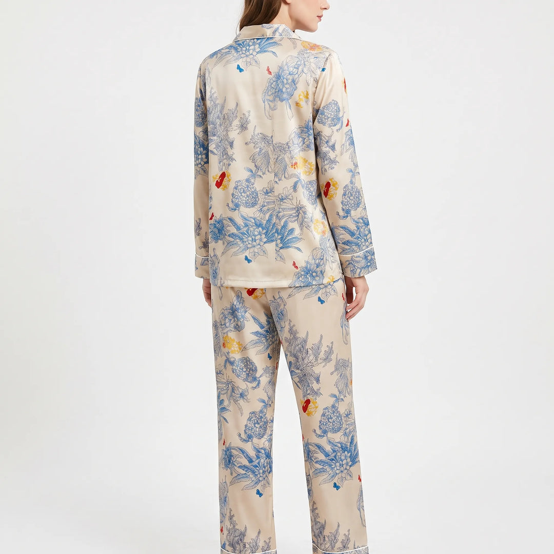 Back view of a model wearing the floral pyjama set, showing the printed back of the shirt and trousers with piped cuffs. 3