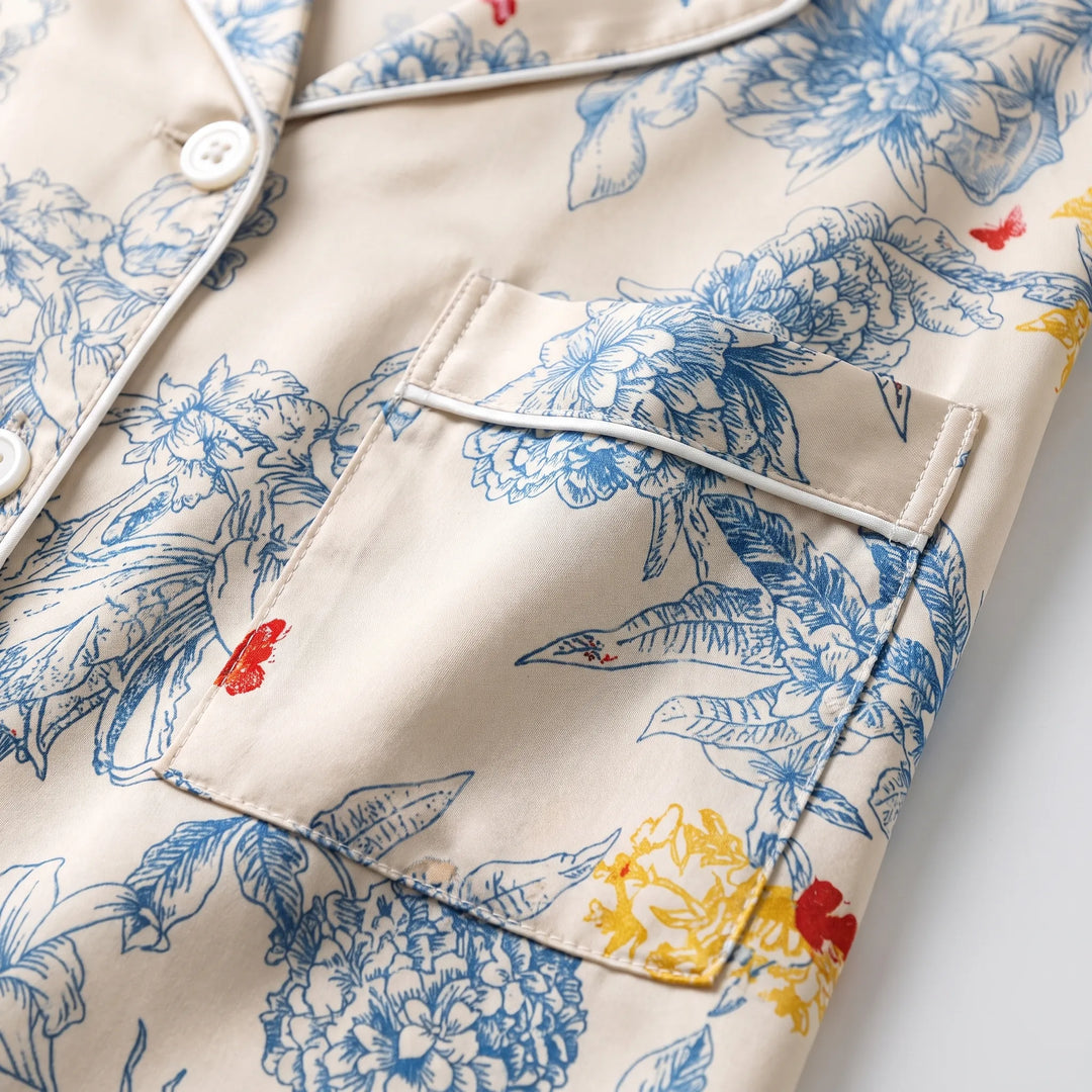 Close-up detail of the chest pocket, white piped edging, pearly buttons and the blue floral print with yellow and red accents. 5