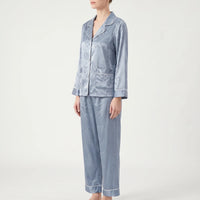 Three-quarter side view of the blue heart-patterned satin pyjamas on a model, showing a patch pocket and piped cuffs. 4