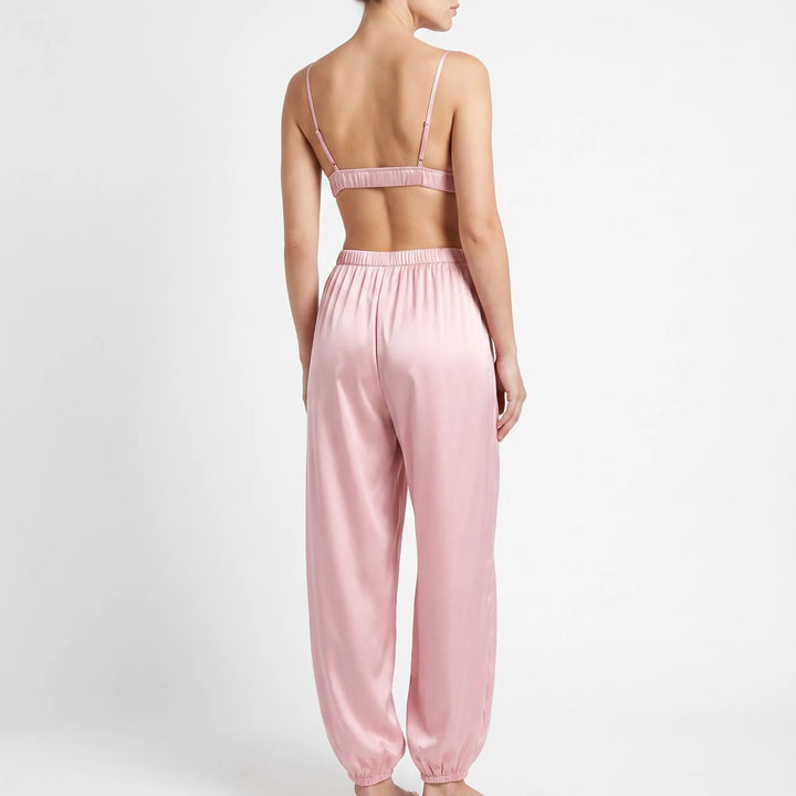Back view of the pink satin set on a model, showing thin adjustable straps, the elastic band of the bralette and pants. 3