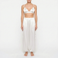 Model wearing the white satin version of the triangle bralette and full gathered trousers, front view on a plain background. 8