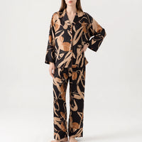 Front view of a model standing with one hand on her hip, wearing the black and tan abstract print pyjama set. 5