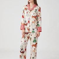Model wearing a cream pyjama print option with dogs in festive costumes, finished with red and white striped collar and cuffs. 12