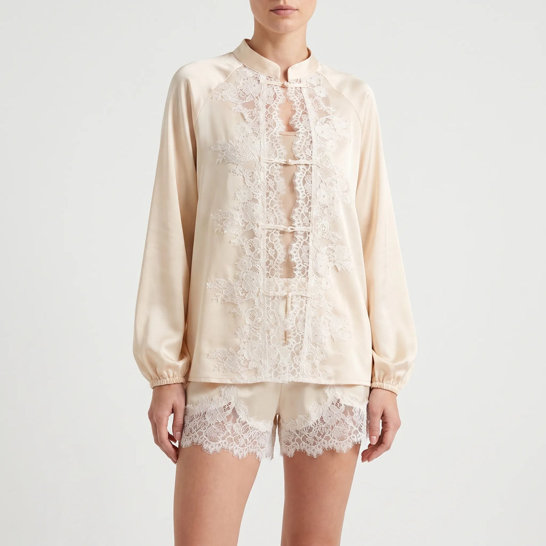Front view on a model against a plain backdrop, showing the lace-covered front opening with knot fastenings, puffed sleeves and lace shorts. 2