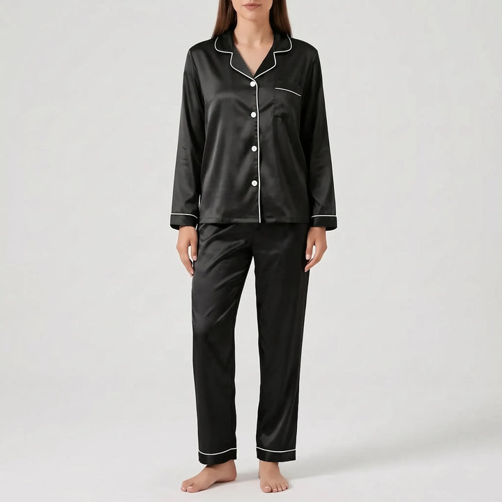 Model wearing the satin pyjama set in black with white piping and white buttons, front view. 13