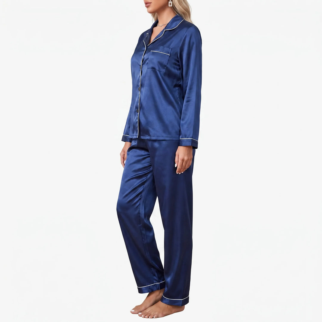 Side view of a model in the navy satin pyjama set, showing the chest pocket, piped cuffs and straight trousers. 4