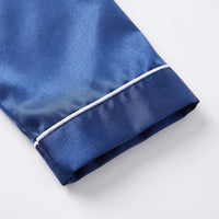 Close-up of a navy satin sleeve cuff with white piping edge on a plain white background. 5