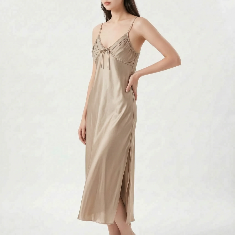 Model with hand on hip wearing the nightdress in a champagne beige satin, with pleated bodice, bow and side slit. 6