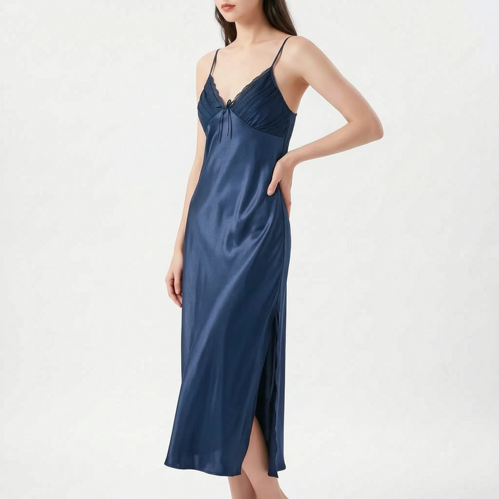 Model with hand on hip wearing the nightdress in navy blue satin, with lace-trimmed pleated bodice, bow and side slit. 9