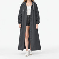 Studio front view of the dark grey hooded raincoat worn open with silver snap buttons and white drawstrings over black shorts. 11