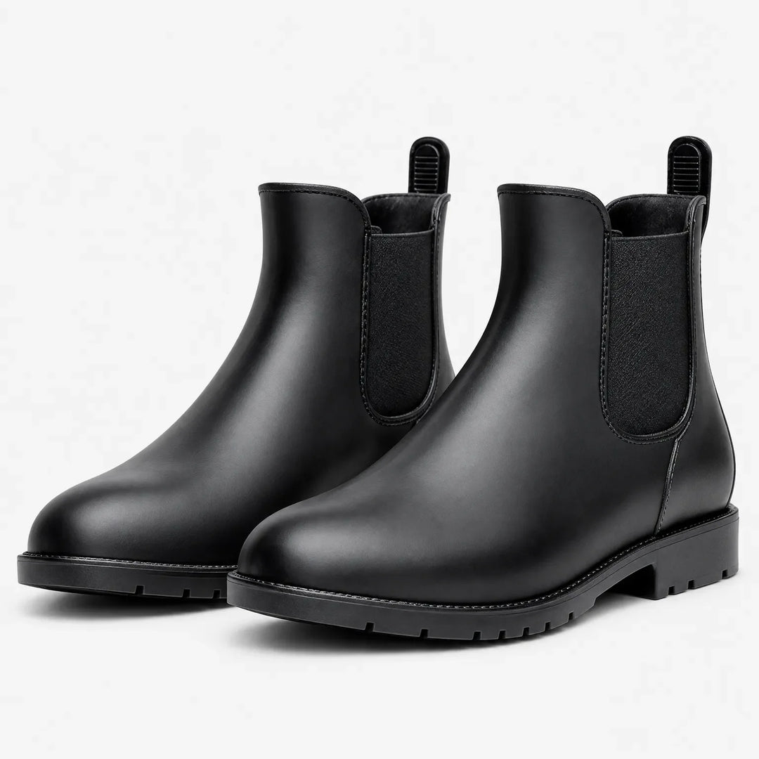 Pair of matte black Chelsea rain boots with elastic side panels and pull tabs, shown at an angle on white. 2