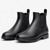 Pair of matte black Chelsea rain boots with elastic side panels and pull tabs, shown at an angle on white. 2