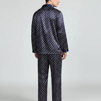 Back view of the navy lattice-print pyjama set on a model, showing the plain back of the shirt and trousers. 3