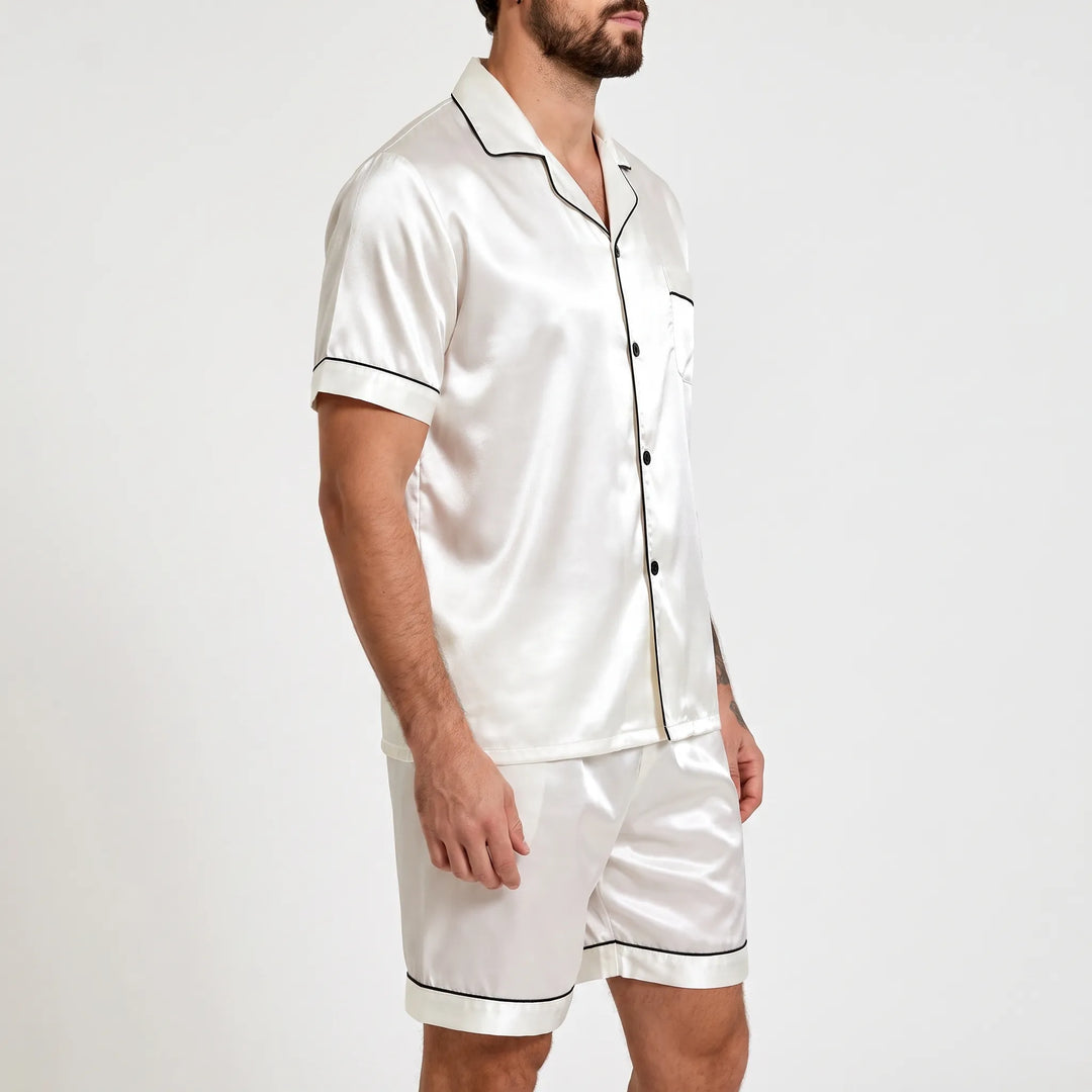 Three-quarter side view of the white satin pyjama set with black piping, showing sleeve, buttons and chest pocket on a model. 4