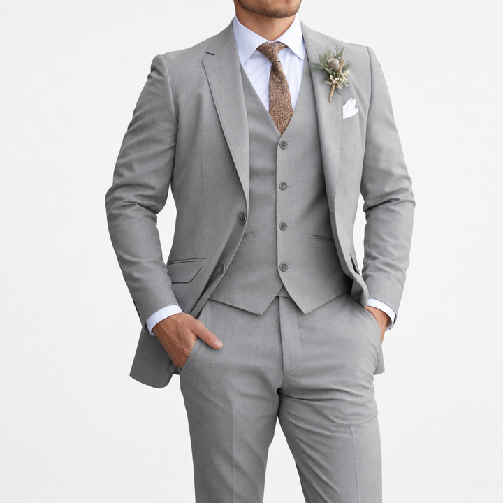 Model in a light grey three-piece suit with white shirt, brown tie and dried-flower buttonhole, on white background 8