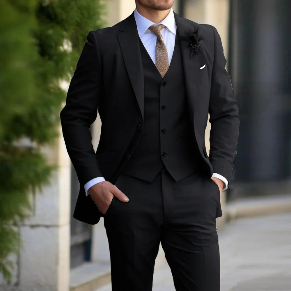 Model wearing the suit in black with matching waistcoat, white shirt and brown tie, hands in pockets 4
