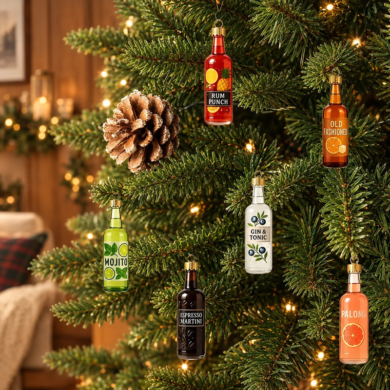 Six colorful miniature glass bottle ornaments with gold caps hanging on a lit evergreen branch beside a pine cone in a cozy room. 1