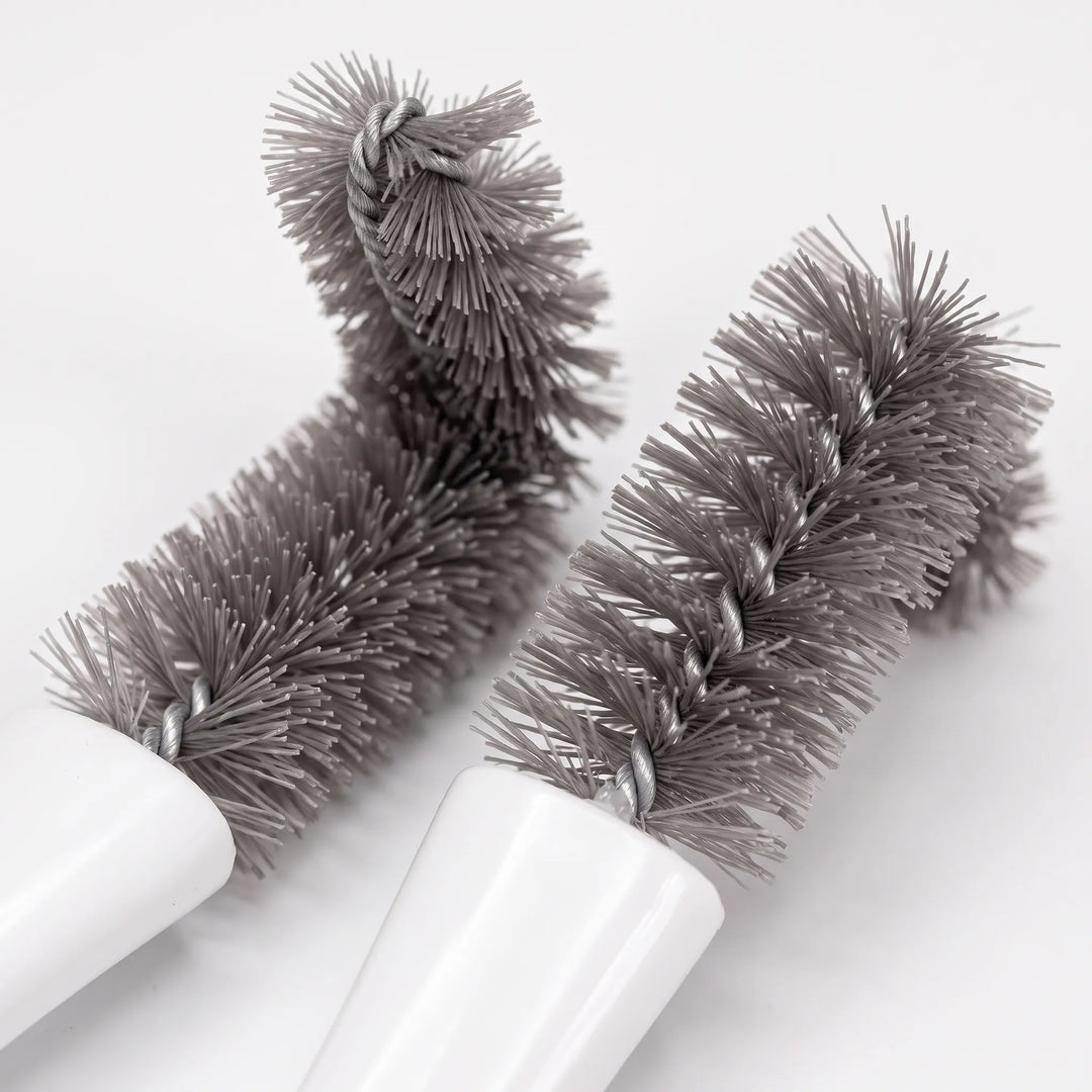 Close-up of two grey twisted-wire brush heads with dense, soft bristles, one bent at a right angle, against a white background. 3