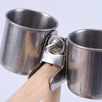 Close-up of two stainless steel food cups held by a metal clamp with a screw fixing them to the wooden perch. 4