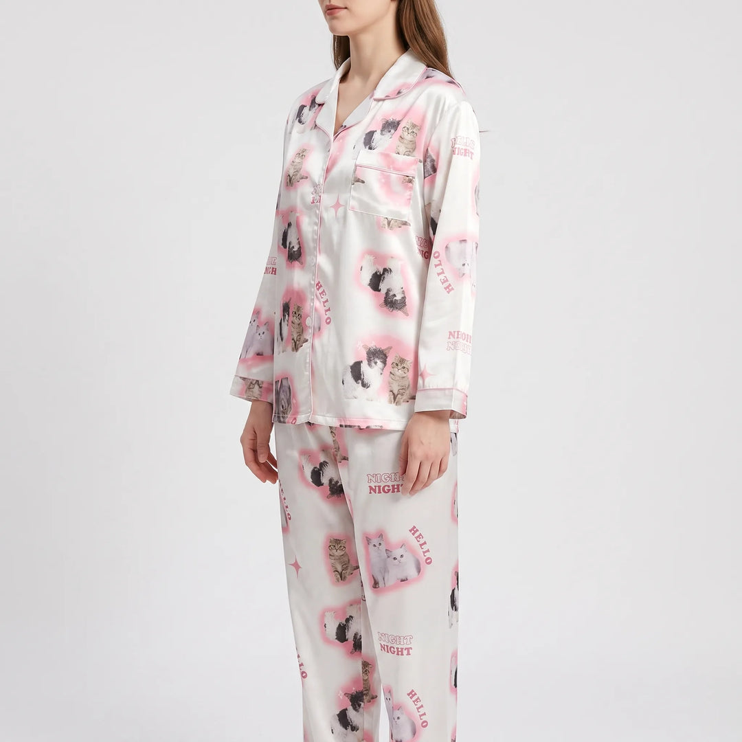 Side three-quarter view of the model in the pink kitten-print satin pyjamas, showing the sleeve and trouser print. 4