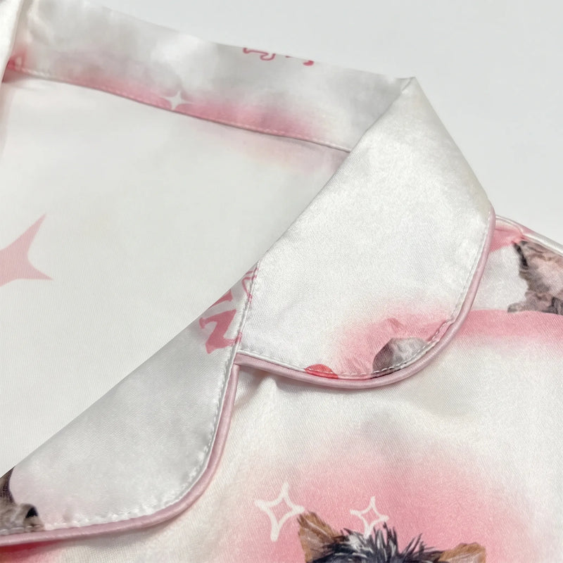 Close-up of the satin collar with pink piping and part of the kitten print on a white background. 5