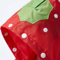 Close-up of the red strawberry-style jacket's hood, showing white snap buttons, white dots, stitching and a green leaf patch. 6