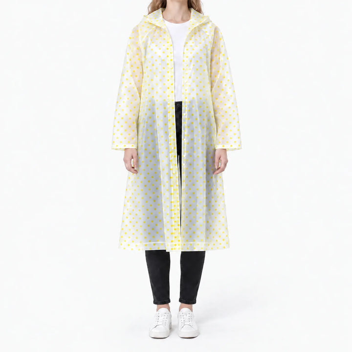 Front view of the translucent raincoat with yellow polka dots, worn open over a white tee and black jeans. 11