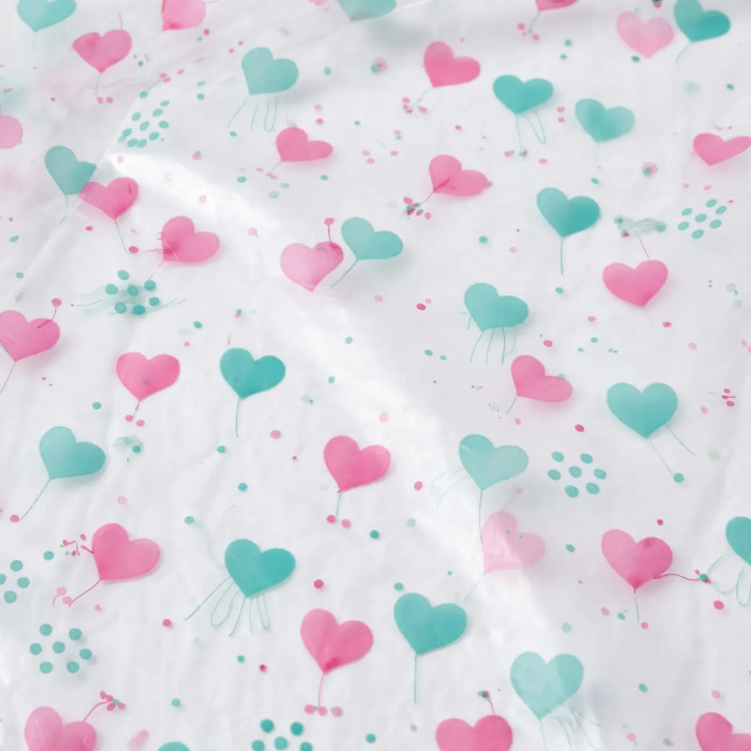 Close-up of the clear plastic material printed with pink and teal hearts and small dots. 6