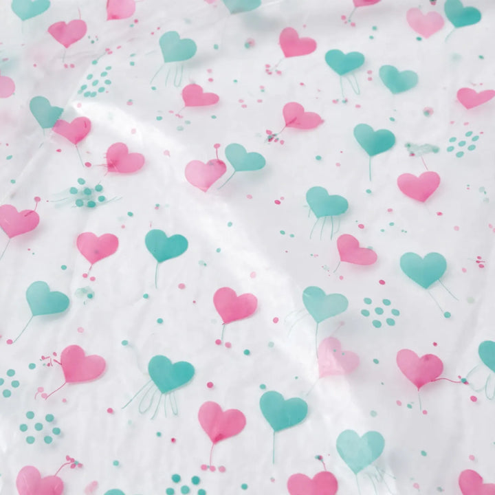 Close-up of the clear plastic material printed with pink and teal hearts and small dots. 6