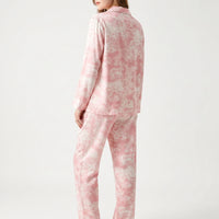 Back view of a model wearing the pink and cream animal-print pyjama shirt and trousers, looking over her shoulder. 3