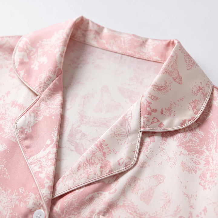 Close-up of the notched collar with piped edging and a white button, showing the pink and cream pastoral print up close. 5